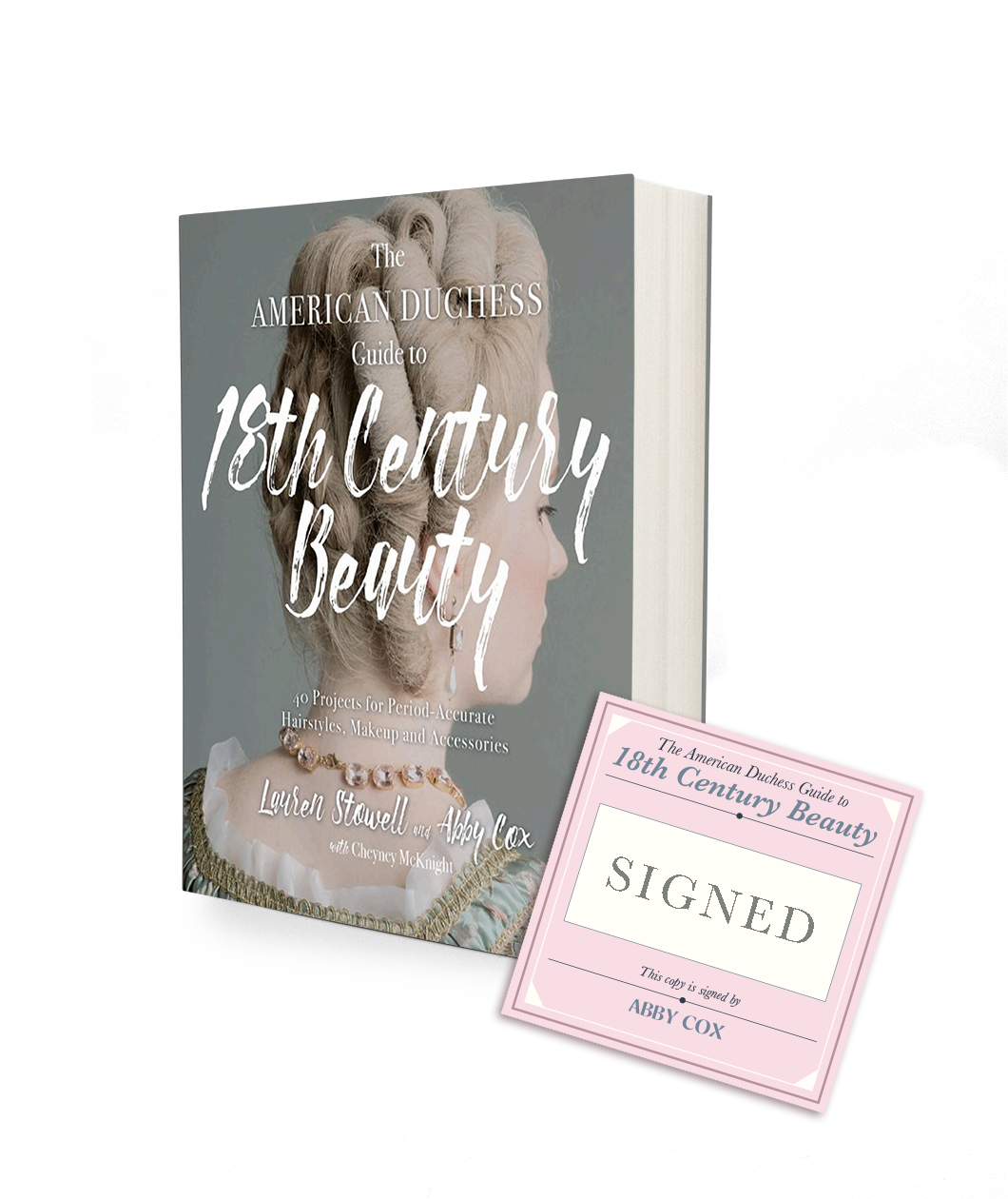 A book with a sage green background and the image of a lady with a white curly wig appearing to be from the 18th century. The title of the book says The American Duchess Guide to 18th Century Beauty. There is a square pink bookplate next to the book that indicates it is signed by the author Abby Cox.