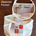 Upper left text says Interior Zippered Pocket and image shows a canvas tote with red and light purple square design on the front. There is a circular image on top that shows the top of the tote unzippered to reveal a smaller zippered pocket on the interior with a pink and gold corset pin sticking out.
