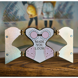 Gold hard enamel pin has either side opened to reveal the words "MADE YOU LOOK" in the center with slightly darker pink padding on each hip and a pink bra with white enamel lace. Small magnets are on the back of the two open front flaps.