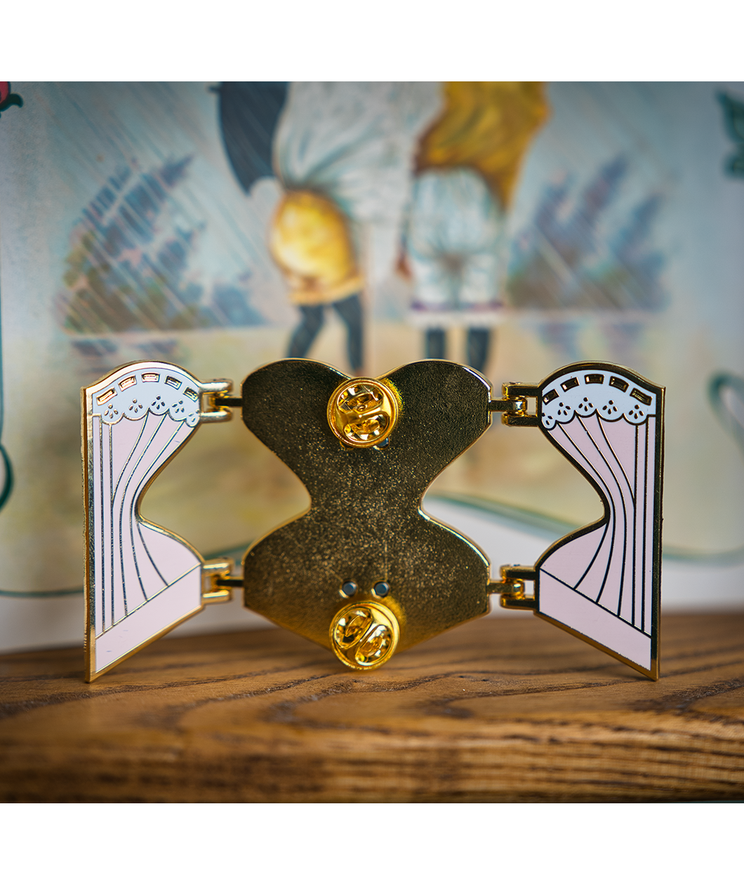 Back of the gold hard enamel pin when it is open and you can see either half of the outer corset on either side connected to the central back piece by four gold hinges. Two gold butterfly clasps are on the top and bottom of the back of the pin to secure it.