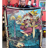 Jesse Cox a red bearded bespectacled man holding the blanket bearing his likeness in cartoon form.