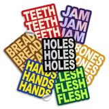 3" vinyl die cut stickers with bold block text. A red sticker with off white text says "TEETH TEETH TEETH". A purple sticker with purple holographic text says, "JAM JAM JAM". A Brown sticker with yellow-tan text says "BREAD BREAD BREAD". A Black sticker with glittery text says, "HOLES HOLES HOLES". A royal blue sticker with yellow text says, "HANDS HANDS HANDS". A green sticker with neon green text says, "FLESH FLESH FLESH". And a mustard colored sticker with off white text reads, "BONES BONES BONES".