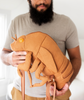 Man holding canvas backpack in the shape of a cicada shell complete with brown straps that attach the front legs to the thorax and egg yolk shaped protruding eyes. 