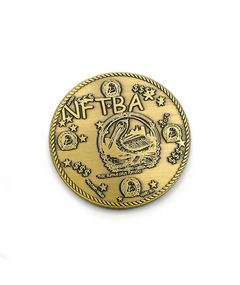 Front of antique gold coin with words NFTBA in comic sans font engraved into it. There is a clipart picture of a pelican with the phrase Hic sumus pius familia in the center-ish. There is a rope design border. There are smaller versions of the pelican image along the sides, stars, and dollar signs. There is a small phrase noting "No cash value" on the bottom.