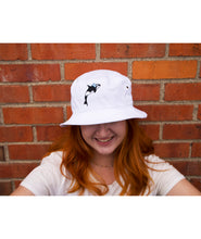 A person's head wearing a white bucket hat with a orca whale on the front. From Scishow.