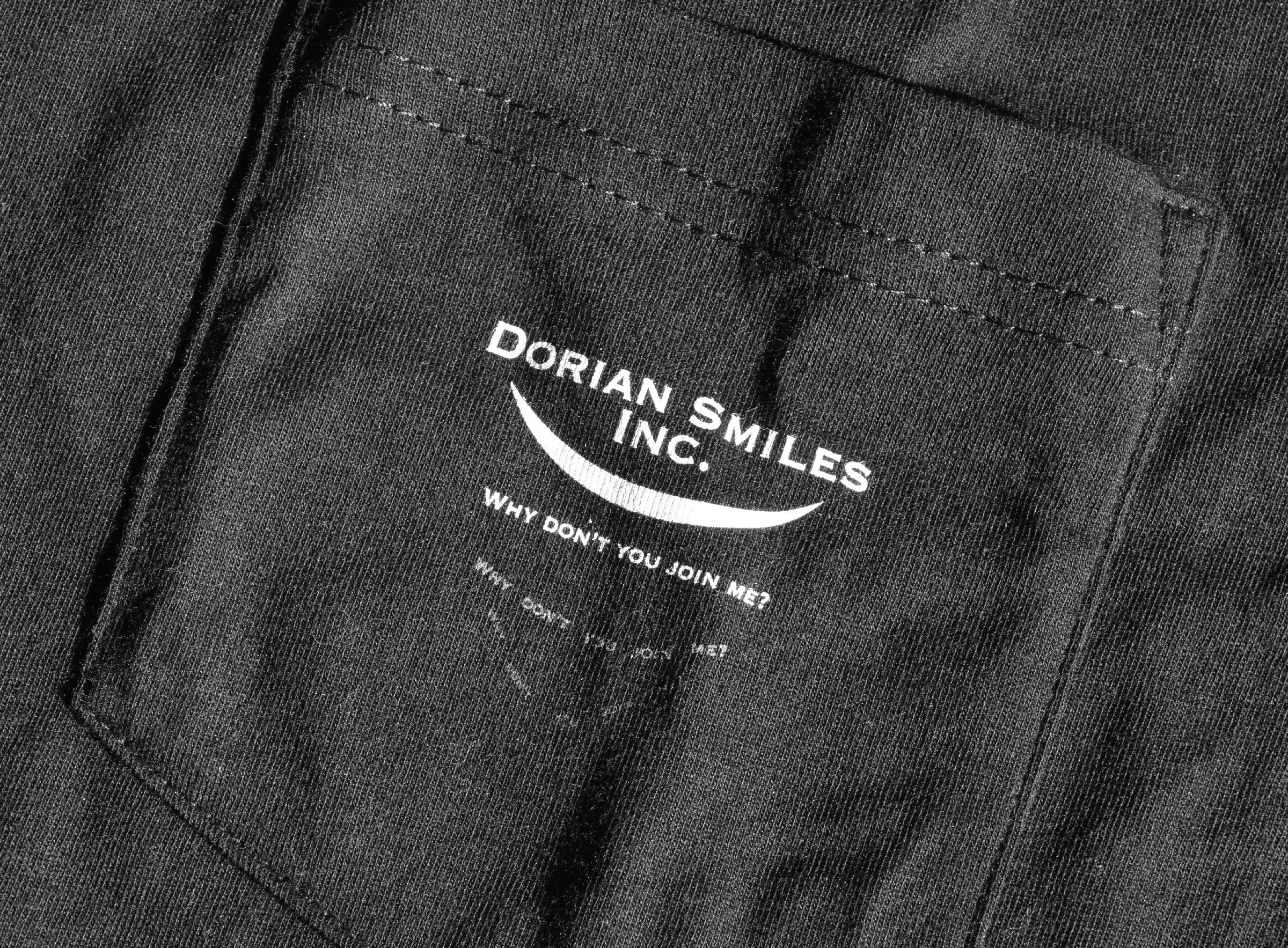 Close-up on a black pocket with the words "Dorian Smiles Inc." over a curved smile and the phrase "Why don't you join me?" in white - by Brian David Gilbert