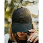 Lizzie Peirce wearing a hat with her head pointed down. The hat is black and is embroidered with "Angle Light Lens."