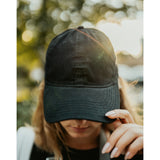 Lizzie Peirce wearing a hat with her head pointed down. The hat is black and is embroidered with "Angle Light Lens."