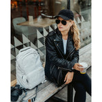 Lizzie Peirce wearing a hat and sunglasses with a camera and backpack next to her.