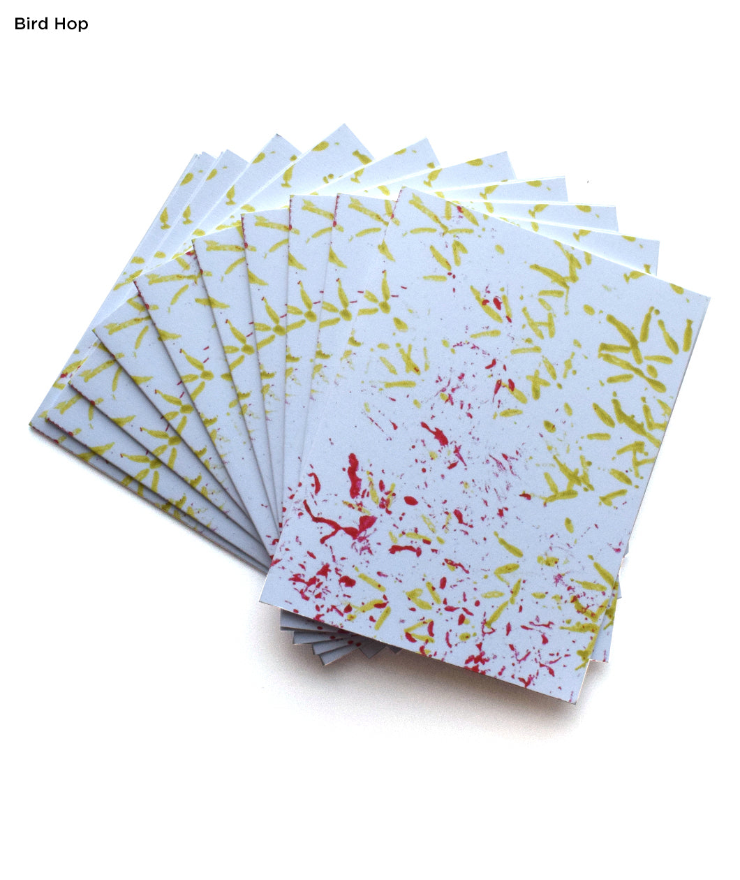 Yellow bird footprints and red sprinkle of seeds. Multple greeting cards are fanned out from behind. “Bird Hop” is written in top left of image in black sans serif font indicating which greeting card is being shown - from Animal Wonders