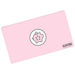 A pink rectangular playmat with curved corners. In the center is a white circle with a black outline. A piggy bank is in the center with a coin being inserted. On the pig are five circles of different colors. “The Commander’s Quarters” is in the bottom right in black sans serif font - from The Commaner’s Quarters