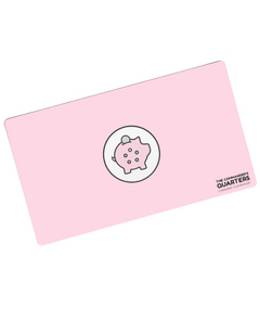 A pink rectangular playmat with curved corners. In the center is a white circle with a black outline. A piggy bank is in the center with a coin being inserted. On the pig are five circles of different colors. “The Commander’s Quarters” is in the bottom right in black sans serif font - from The Commaner’s Quarters