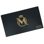 A black rectangular playmat with curved edges. In the center, a gold stylized M is in front of a gold circle. A gold crown is above. “The Commander’s Quarter Millions” is in the bottom right in gold serif font - from the Commander’s Quarters