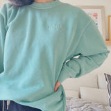 Mayuko Inoue modeling a mint green crewneck sweater with “code;” embroidered in the top right of the sweater in mint green - from Hello Mayuko
