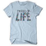 Light blue shirt with “I’m Full Of” in black sans serif font across chest. Below, “Life” is written and made up of various cartoon drawn microbes and bacteria of varying colors - from Minute Earth
