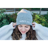 A woman modeling a gray beanie with “confident & kind” in white cursive font across the cuff - from Sierra Schultzzie