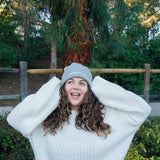 A woman modeling a gray beanie with “confident & kind” in white cursive font across the cuff - from Sierra Schultzzie