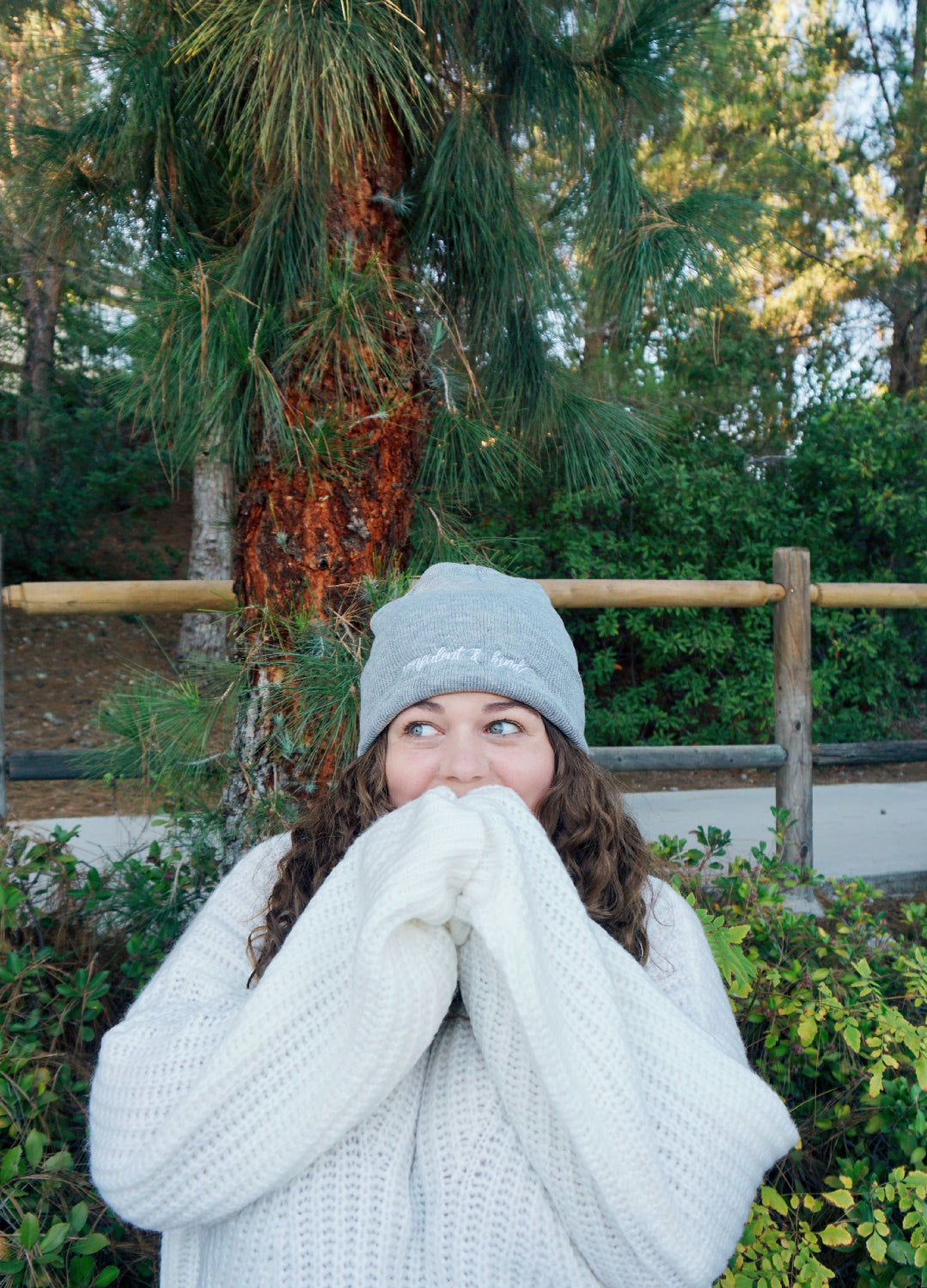 A woman modeling a gray beanie with “confident & kind” in white cursive font across the cuff - from Sierra Schultzzie