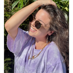 Someone wearing the lavender confident and kind crop top from Sierra Schultzzie, facing the sunshine, wearing sunglasses an holding their arm up to their head, smiling.