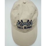 A top view of a beige ball cap with the embroidered words "Full Bloom" and flowers from Sierra Schultzzie.