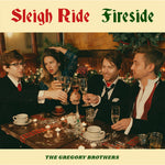 An album cover featuring four people posed in suits and a dress, sitting around a festive table, clinking glasses. On the cover it reads "Sleigh Ride Fireside; The Gregory Brothers".