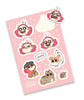 A rectangular pink sticker sheet that contains 9 stickers. 4 of the stickers are the head of a grl with pink hair in various expressions, and the other are a cat, a dog, a snail, the same girl crouched with a beanie, and a word balloon that says "Beret!"