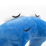 A closeup of a blue neck pillow in the shape of a pi character. The pillow is blue, and the pi character has a sleeping face. From 3Blue1Brown.