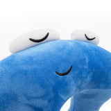 A closeup of a blue neck pillow in the shape of a pi character. The pillow is blue, and the pi character has a sleeping face. From 3Blue1Brown.