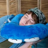 A person laying down and using a neck pillow to sleep. The person is using a neck pillow that is in the shape of a blue pi character. From 3Blue1Brown.