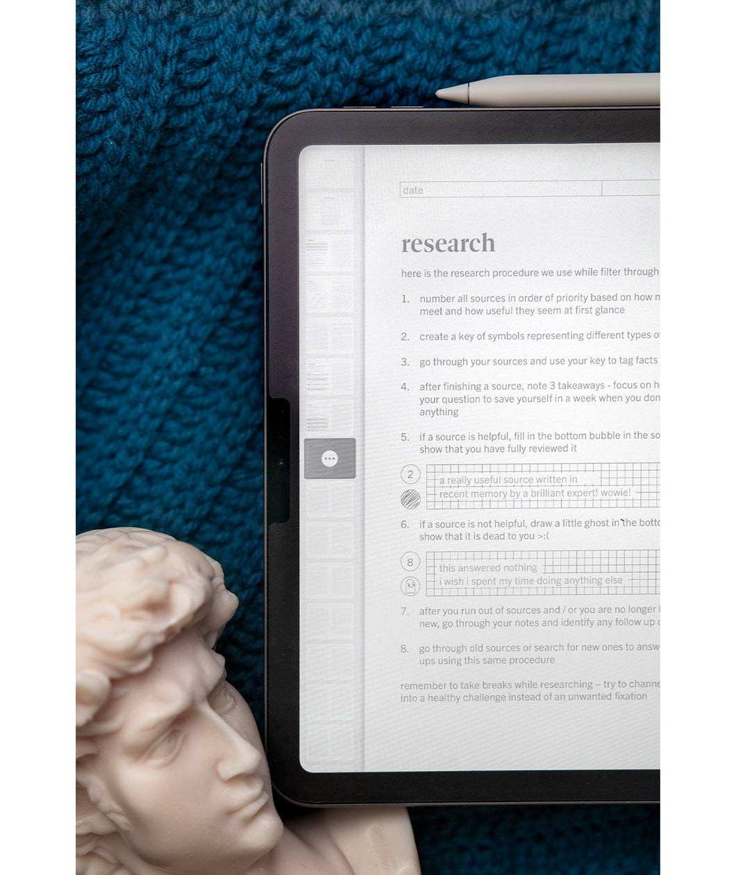 A tablet with a bust head in the left hand corner with half a tablet showing writing and a heading that says "Research". From the curiosity journal from Answer in Progress.