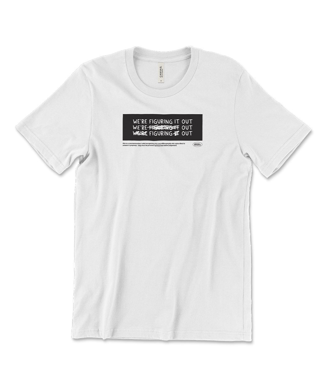 A white t-shirt with a black rectangle in the center with the words "We're figuring it out" written three times in a row with the second line has "figuring" crossed out and the third line has "we're" and "it" crossed out. There is additional small text below this. From Answer in Progress.