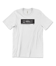 A white t-shirt with a black rectangle in the center with the words "We're figuring it out" written three times in a row with the second line has "figuring" crossed out and the third line has "we're" and "it" crossed out. There is additional small text below this. From Answer in Progress.