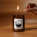 A candle about to be lit by a match. The candle’s label has a design of a person enjoying a bubble bath, with the title, “After Hours, coconut soy wax candle”. From Answer in Progress.