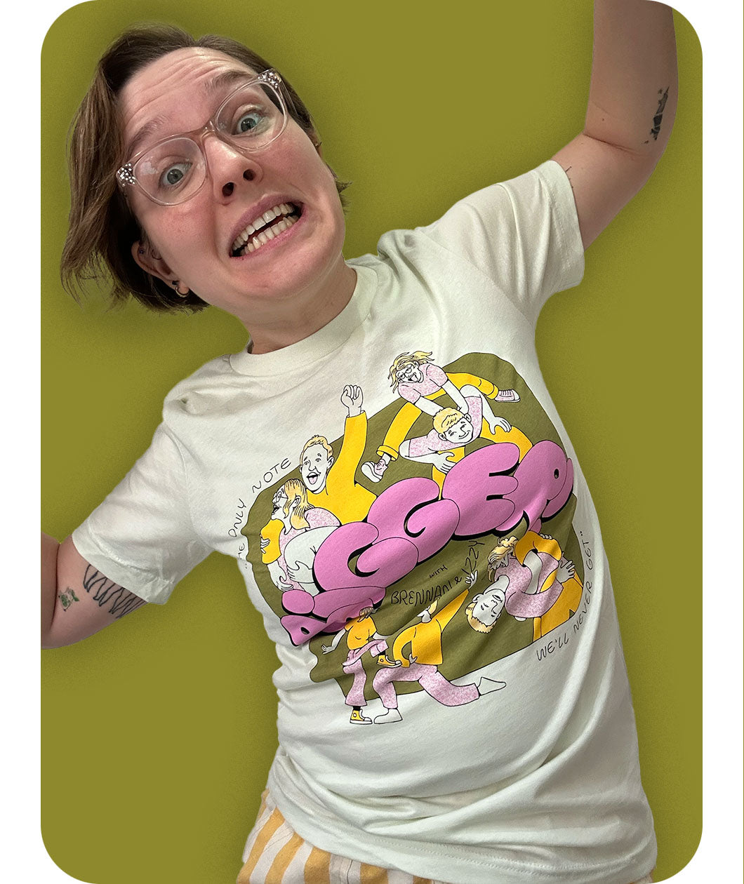 Izzy modeling the Izzy & Brennan's Shenanigans shirt with a funny face against a green background.