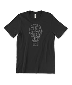 A black t-shirt with a lightbulb in the center made up of small, white text with negative space that reads "Stay Strange". From Atypical Artists.