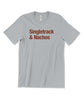 A silver/gray t-shirt with maroon lettering across the front that reads "Singletrack & Nachos". From Courtney Dauwalter.