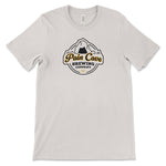 An off-white t-shirt with a design of a fake brewing company logo on the front. The logo is of a cave with the text, "Pain Cave Brewing Company" beneath it. From Courtney Dauwalter.
