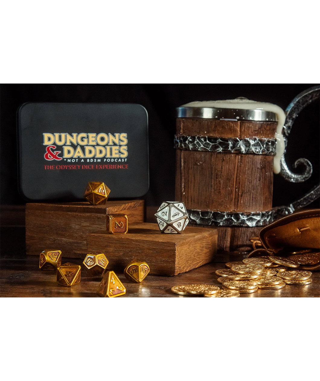 Black Dice holder with Dungeons & Daddies logo, tagline: Not a BDSM Podcast and the title of the Dice Set. Pirate themed set up with gold dice and Honda Odyssey white d20. Gold coins are also on the table with a wooden beer stein overflowing with foam behind them.