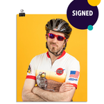 Photo of a man crossing his arms in a zip up bike shirt, bike helmet, and sun glasses smirking at the camera. On a yellow background. This print is signed by the doctor!