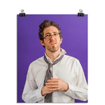 Photo of a man with his glasses askew on his face and ruffled tie and white dress shirt. He looks confused. On a purple background.