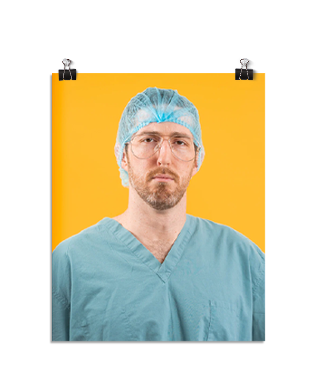 Photo of a man in seafoam colored scrubs and aviator shaped glasses wearing a seafoam hair net looking stone faced at the viewer. On a yellow background.