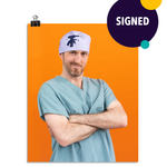 Photo of a man in seafoam colored scrubs and a light purple head wrap with an embroidered hand holding a drill. His arms are crossed as he leans to his right and smirks at the viewer. On an orange colored background. This print is signed by the doctor!