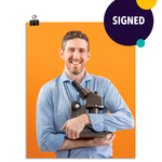 Photo of a man with a large smile wearing a light blue dress shirt as he holds his microscope to his chest like a proud father. On an orange background. This print is signed by the doctor!