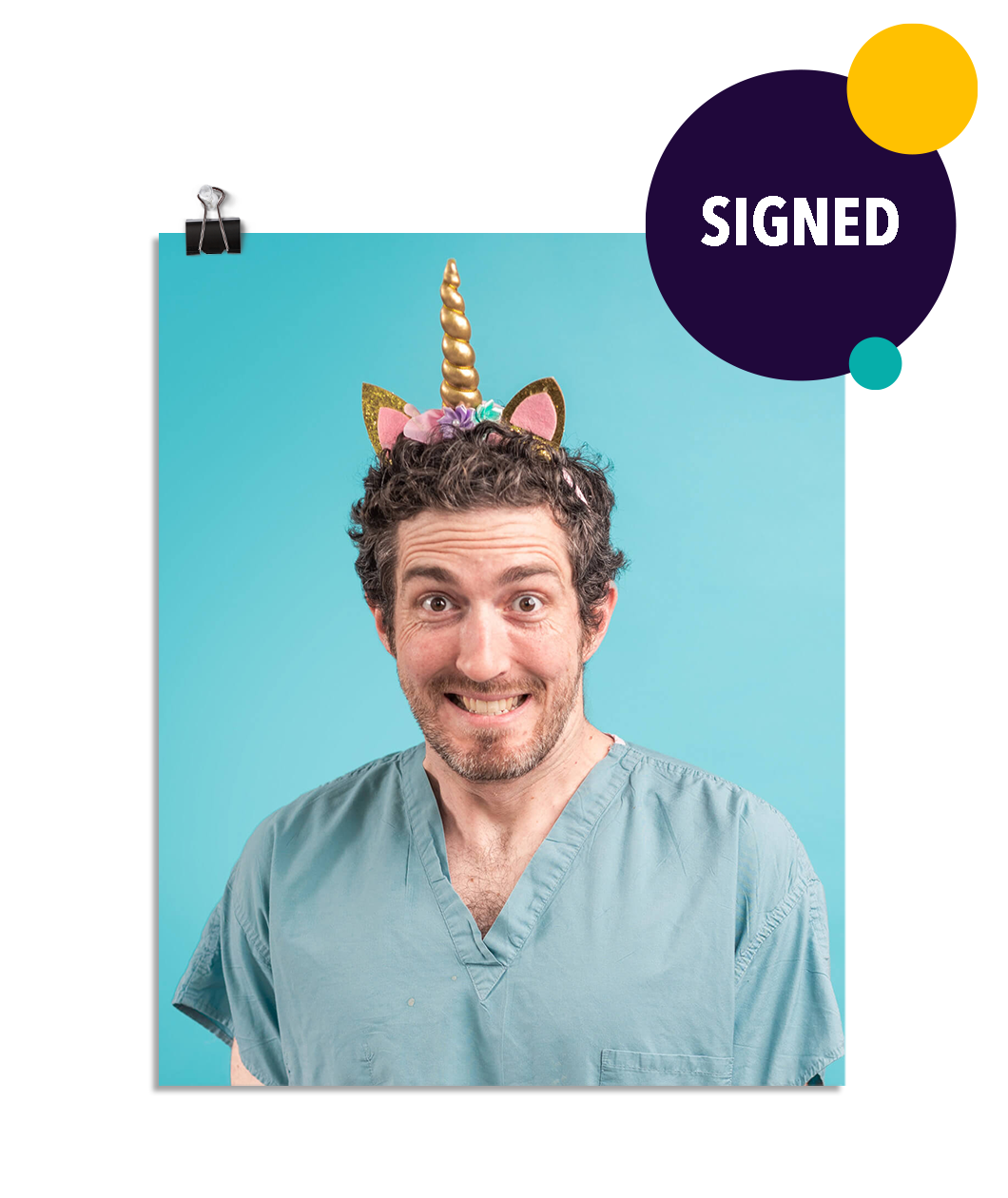 Photo of a man with an almost manic looking smile as he wears seafoam colored scrubs and a glittering gold unicorn horn headband on his head. On a seafoam colored background.This print is signed by the doctor!