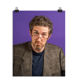 Photo of a man with his glasses notched low on his nose looking at the viewer with raised eyebrows. He is wearing a tweed suit jacket with a navy t shirt underneath and you can tell you did something to upset him. On a purple background.