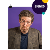 Photo of a man with his glasses notched low on his nose looking at the viewer with raised eyebrows. He is wearing a tweed suit jacket with a navy t shirt underneath and you can tell you did something to upset him. On a purple background. This print is signed by the doctor!