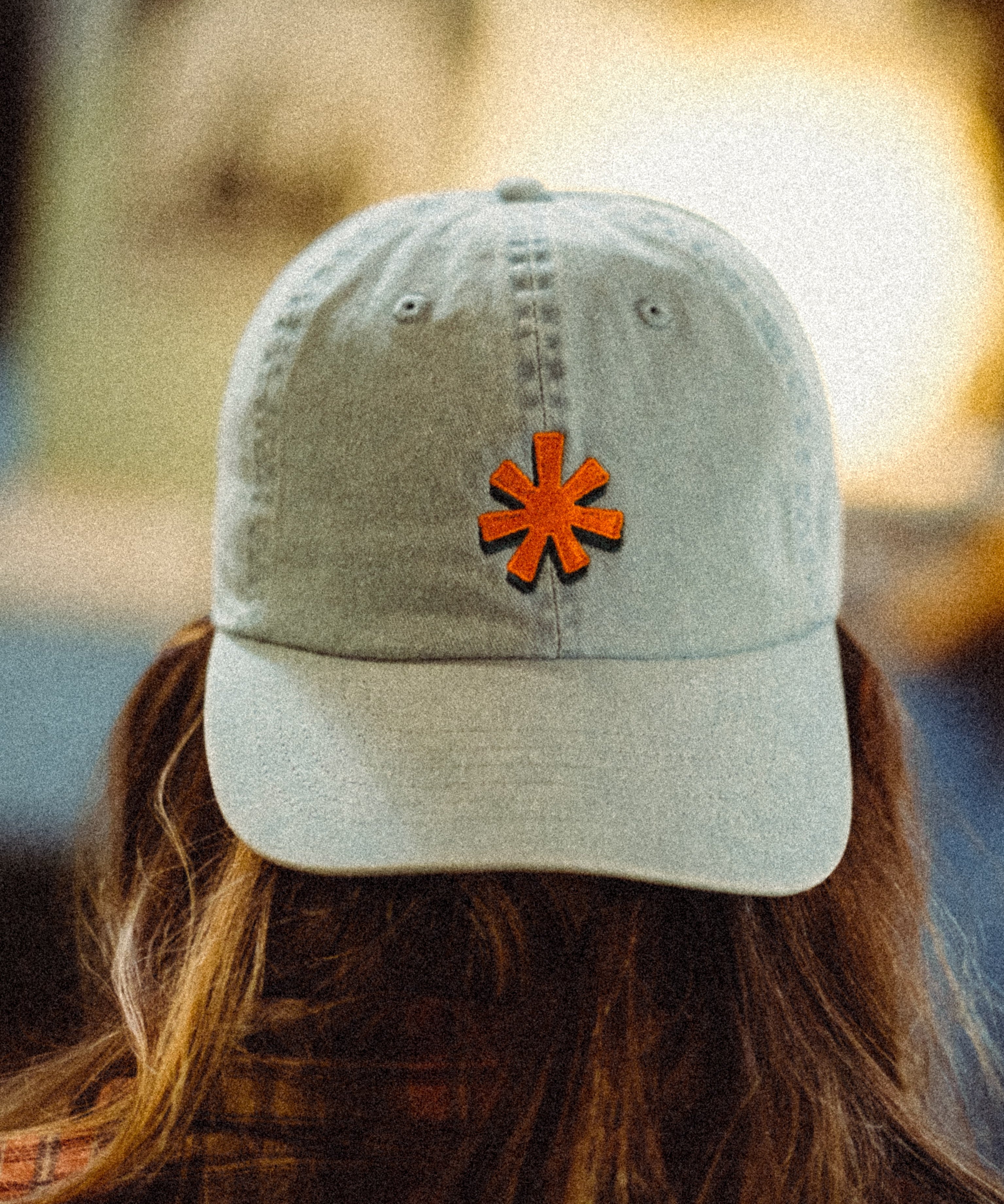 Light denim colored hat with orange asterisk embroidered on the front center.