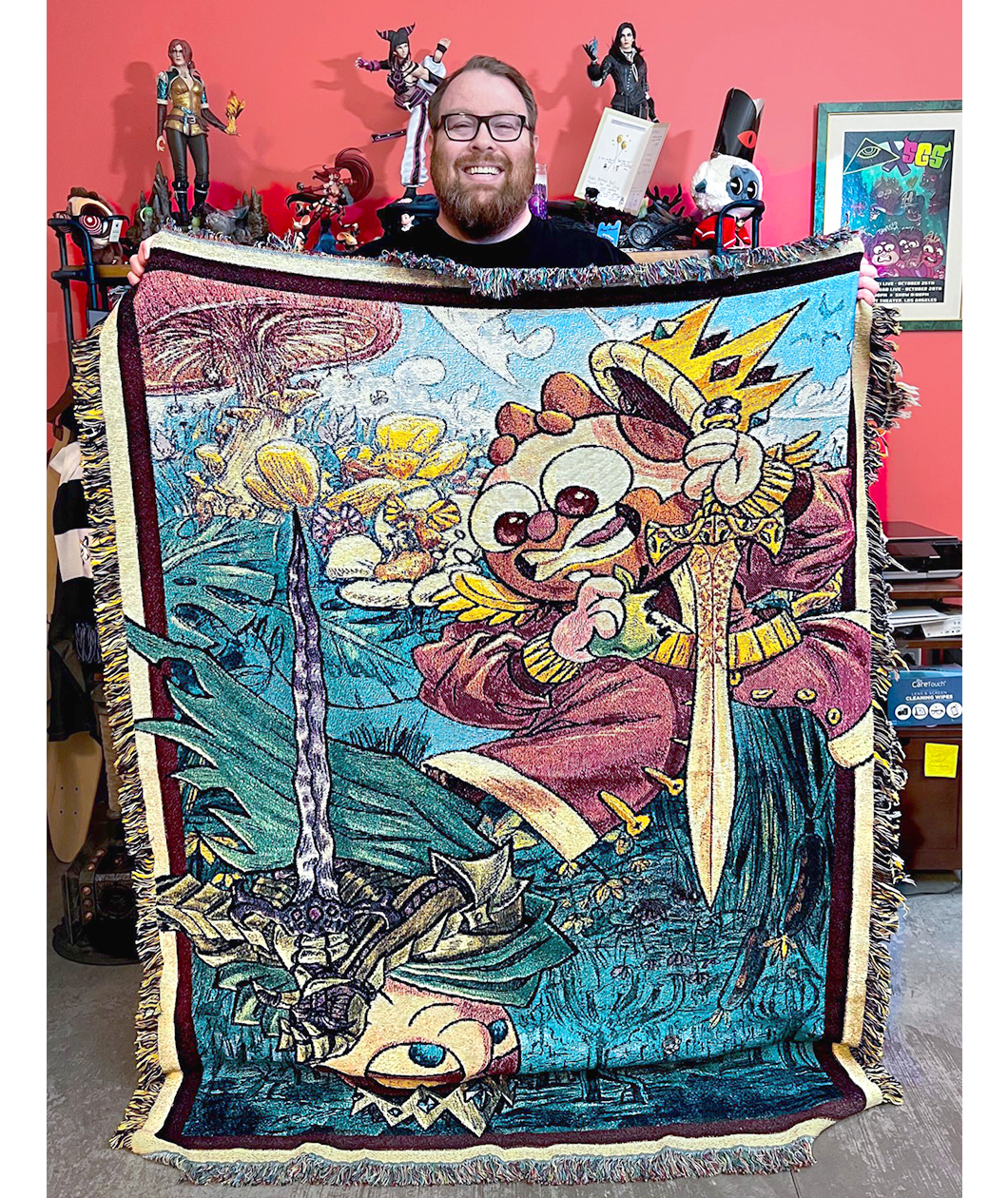 Jesse Cox a red bearded bespectacled man holding the blanket bearing his likeness in cartoon form. 