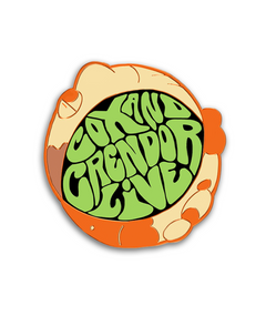 Pin with orange dyed metal plating that has the cartoon faces of Cox and Crendor on either side with the words "COX AND CRENDOR LIVE" in a green groovy font in the center with a black background. Pin is an approximately round shape with the faces being side views shaped like crescent moons.