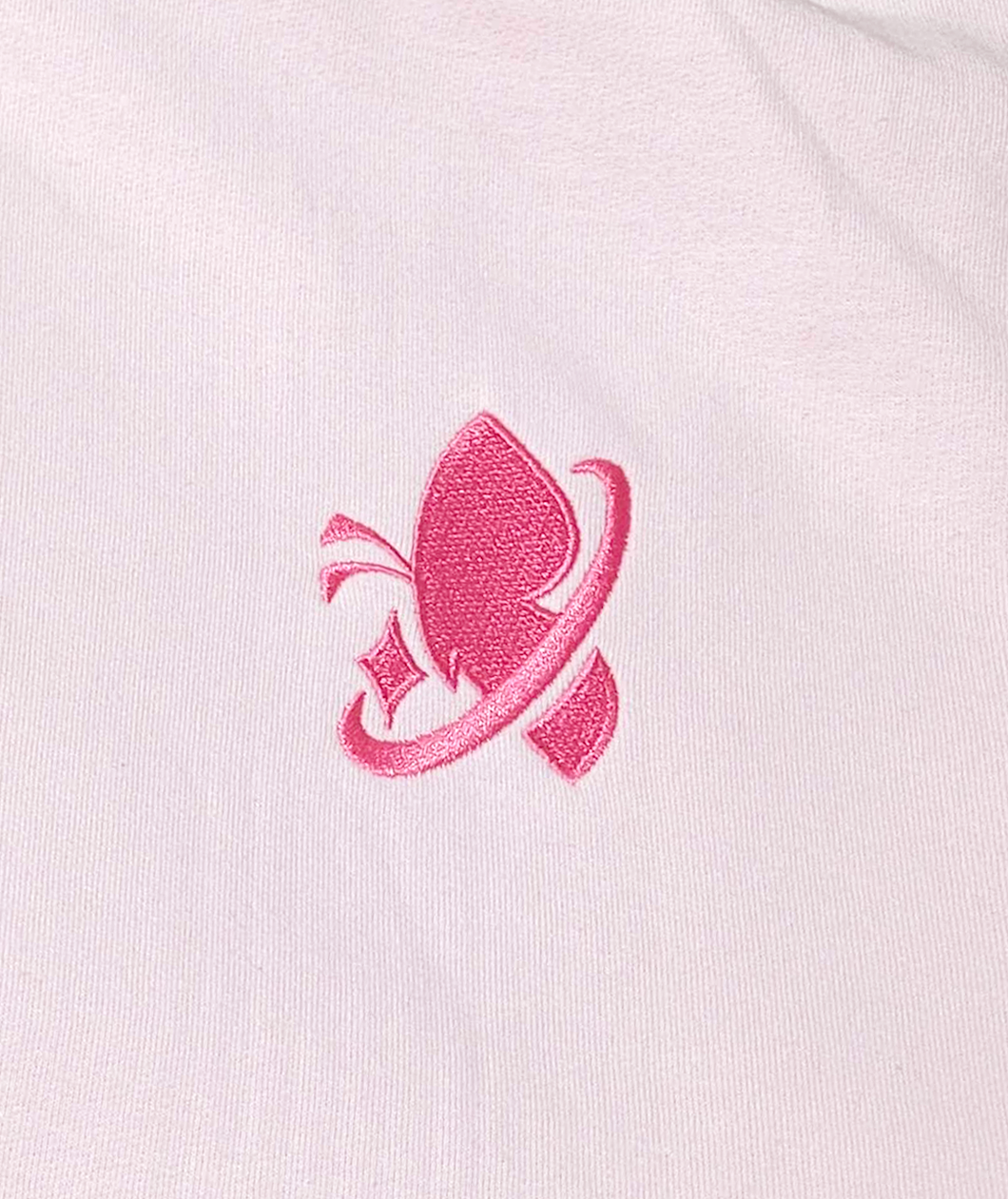 Close up image of the embroidered space butterfly logo. It is a butterfly side profile silhouette with a diamond shaped star to the left of its antenna and a swooping half circle cutting through it similar to the nike logo.